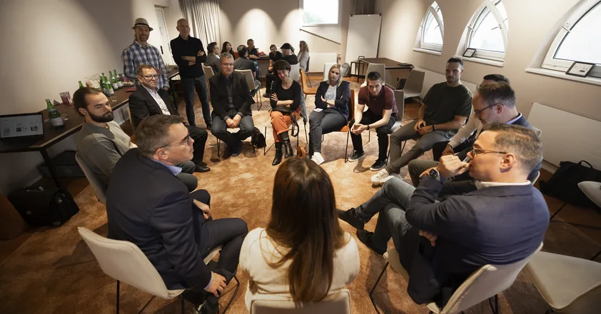 Gesprächsrunde im Stuhlkreis beim KI-Café, im Hintergrund das MMIND.ai-Team